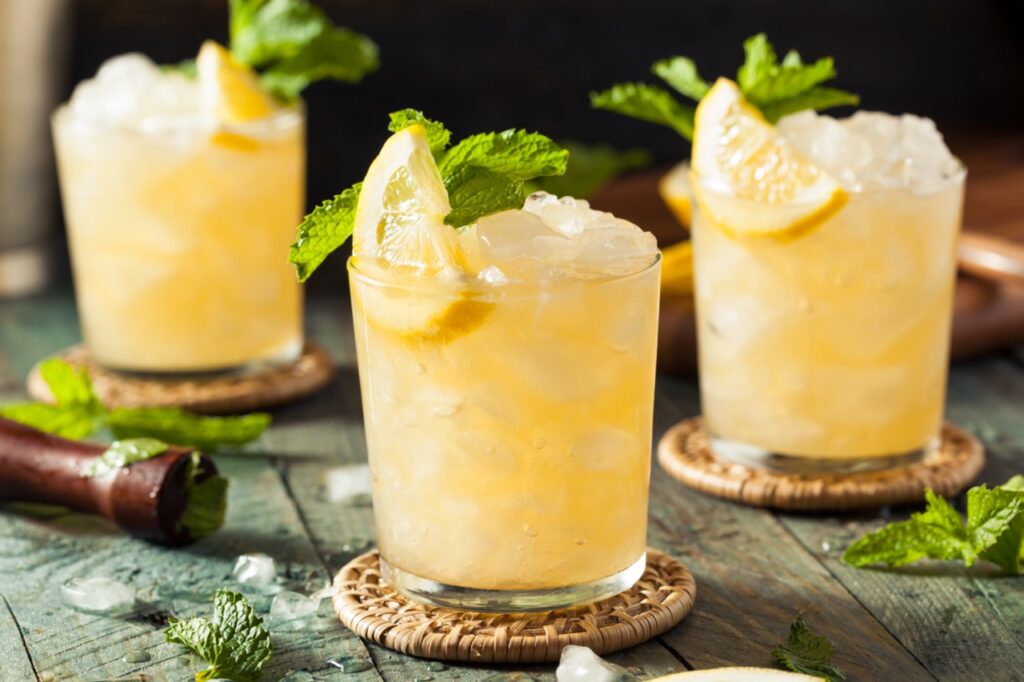 Homemade boozy bourbon whiskey smash with lemon and mint is a drink idea for a day at the races fundraiser theme.