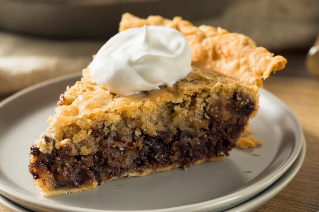 Homemade chocolate walnut derby pie with whipped cream is a dessert idea for a day at the races fundraiser theme.