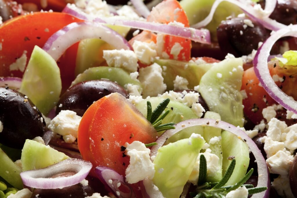 Greek salad, in closeup.  Tomatoes, black olives, red onions, cucumber, rosemary and feta cheese.