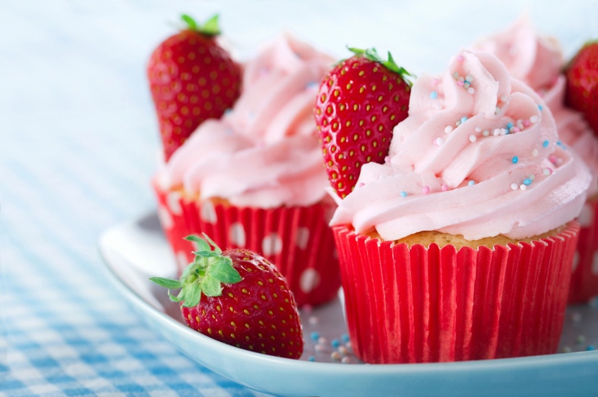 A cupcakes with pink frosting and strawberries on a plate