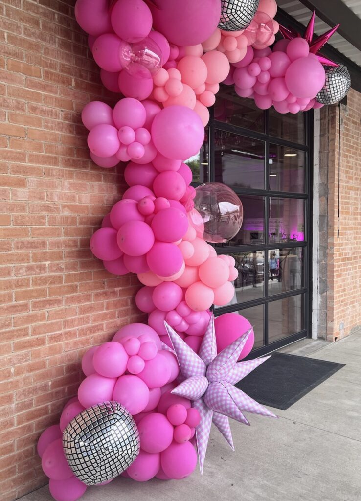 A pink and silver balloons on a brick wall makes a great entrance for a Barbie-Themed Fundraiser event 