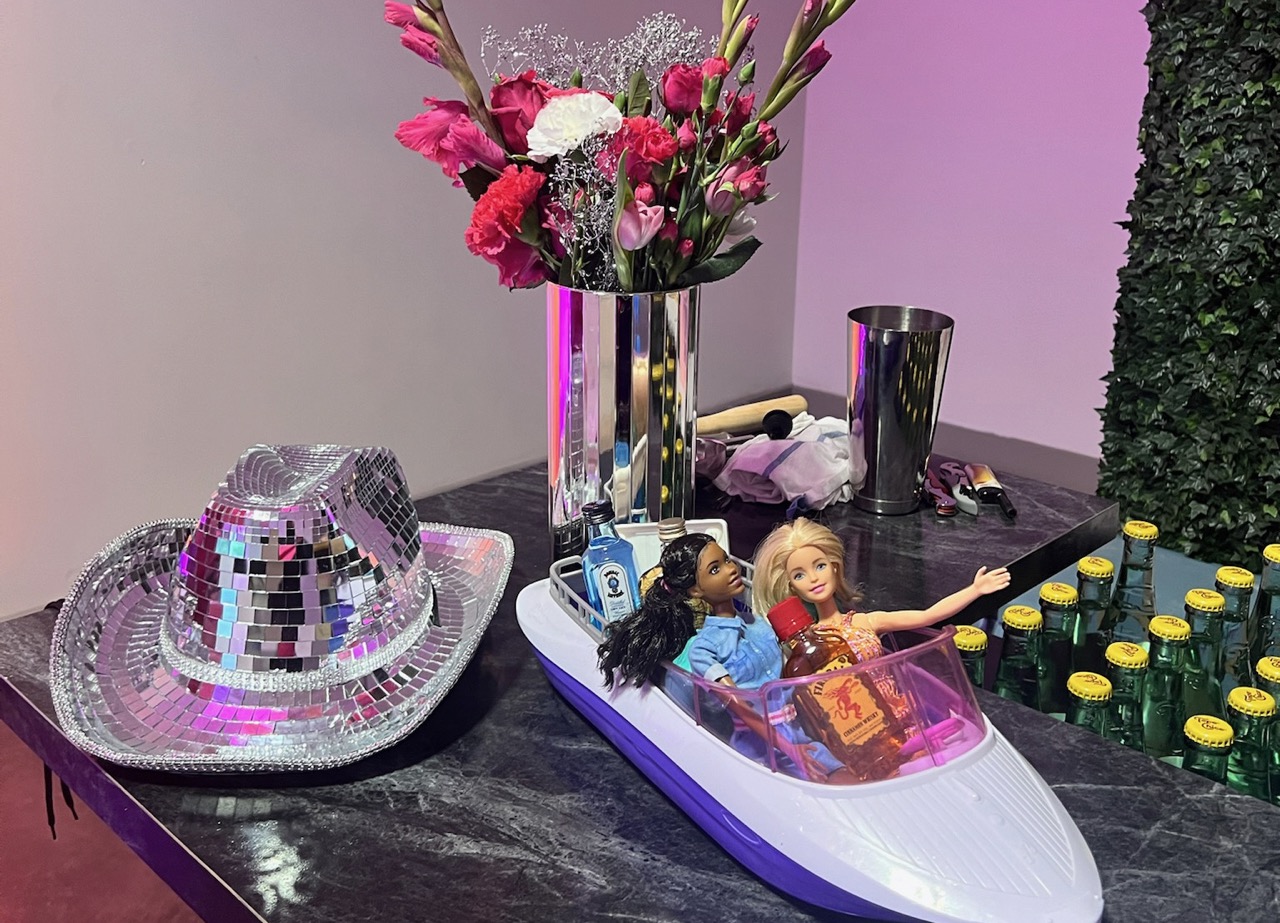 A toy boat with barbie dolls and a hat at a Barbie-Themed Fundraiser event