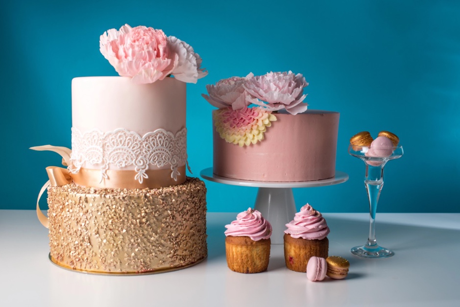 A cake with pink frosting and cupcakes

Description automatically generated
