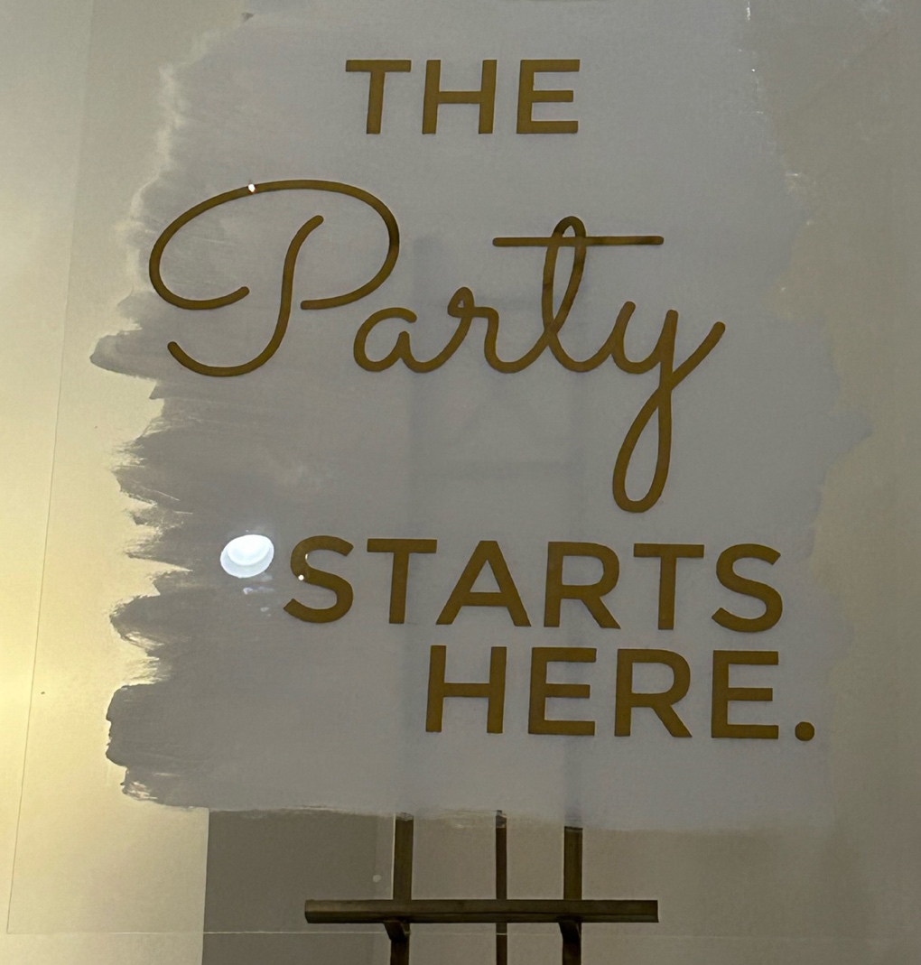 A sign on a wall saying the party starts here is a great wedding theme fundraiser venue decor idea