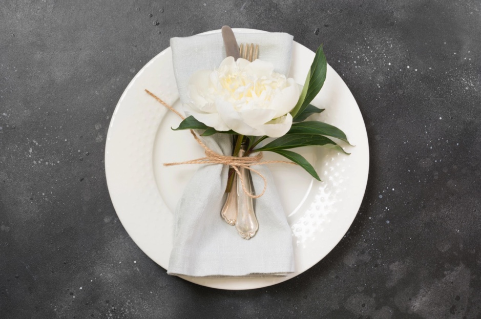 A white flower on a white plate is a great wedding theme fundraiser venue place setting idea