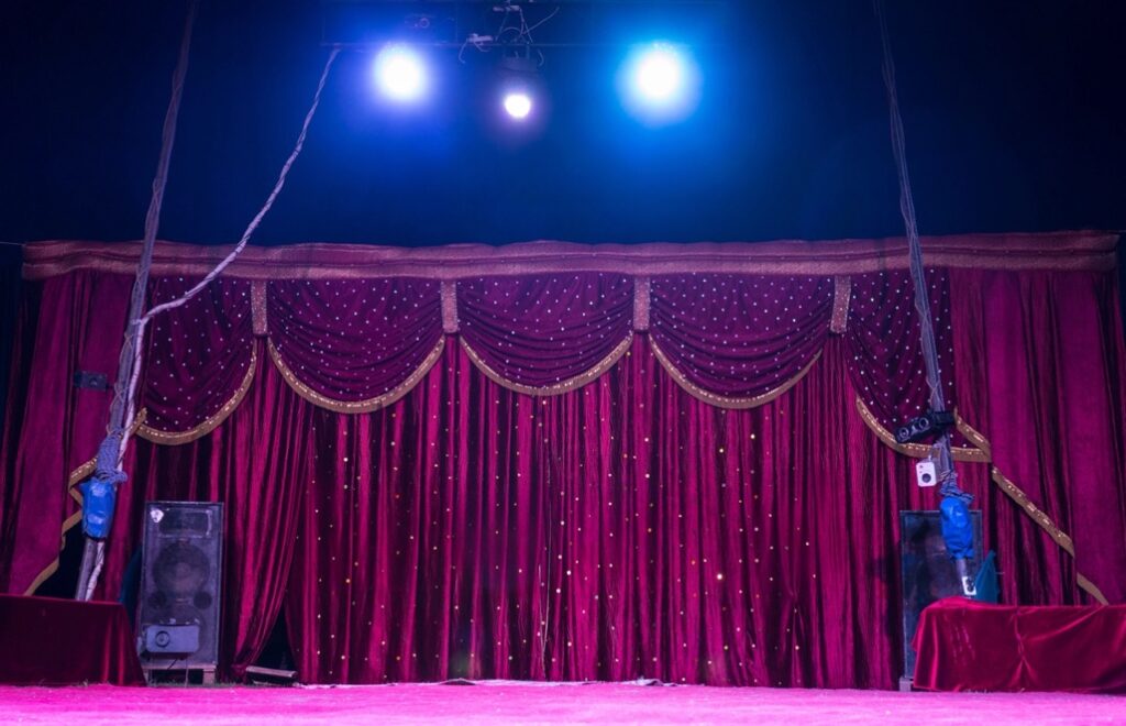 A stage with a red curtain and lights are great Venue Décor for a circus fundraiser theme.