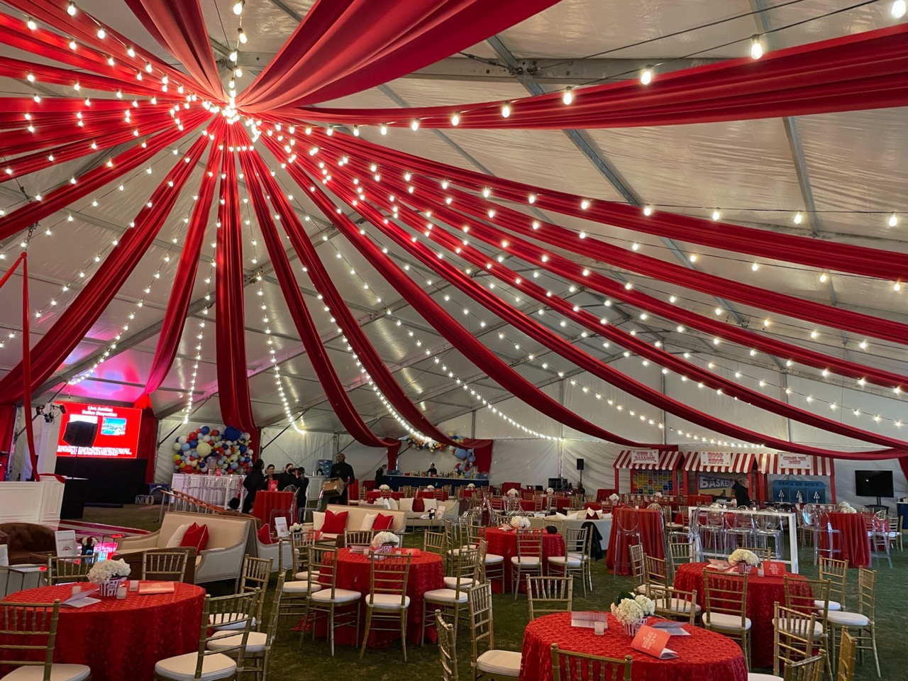 A tent with red curtains and tables and chairs are great Venue Décor for a circus fundraiser theme.
