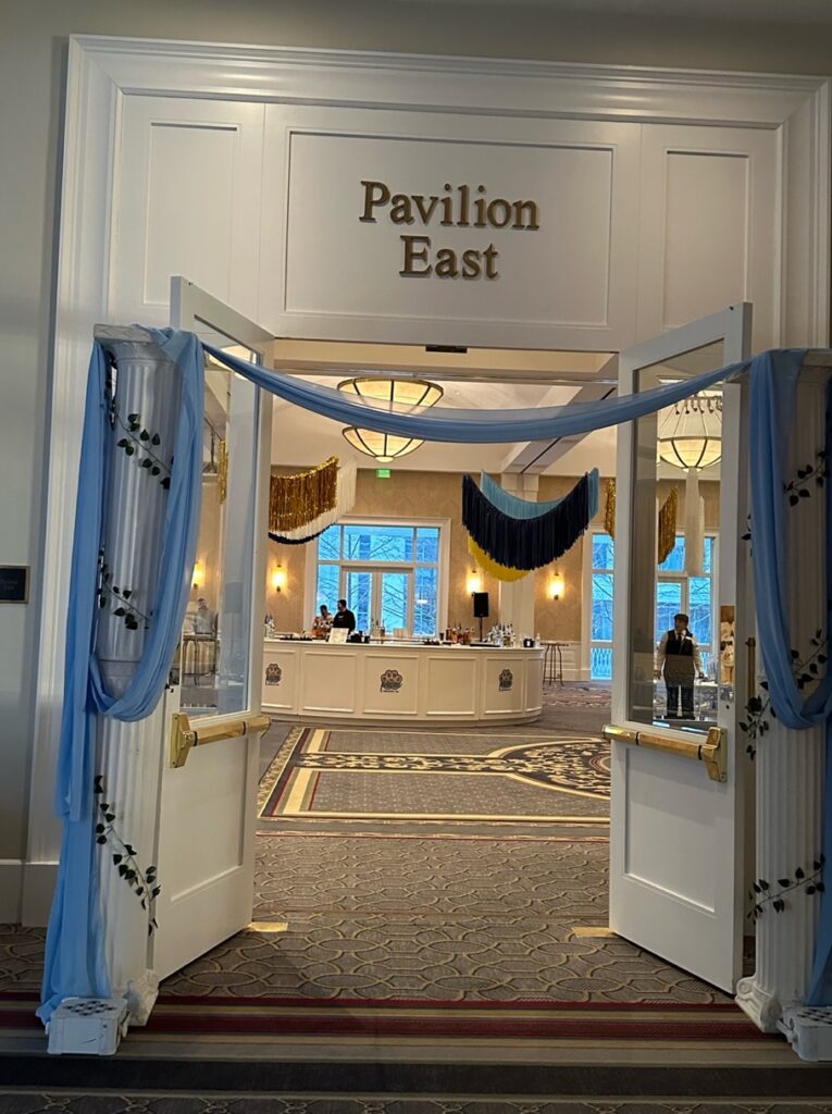 A room with a large white wall and a large white counter with a blue curtain make a great prom themed fundraiser decoration.