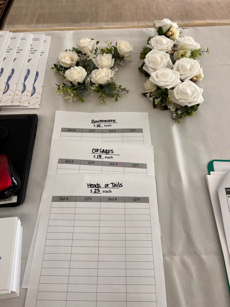 A table with white flowers and accessories for a prom themed fundraiser.