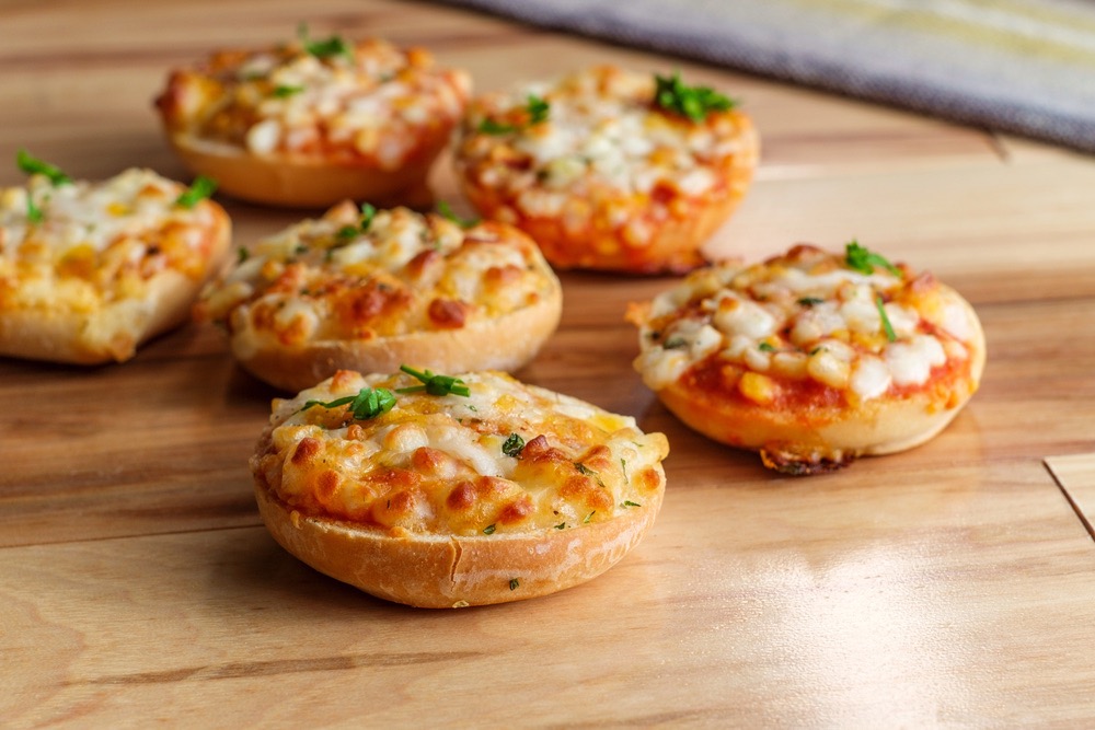 A group of small pizzas on a wood surface