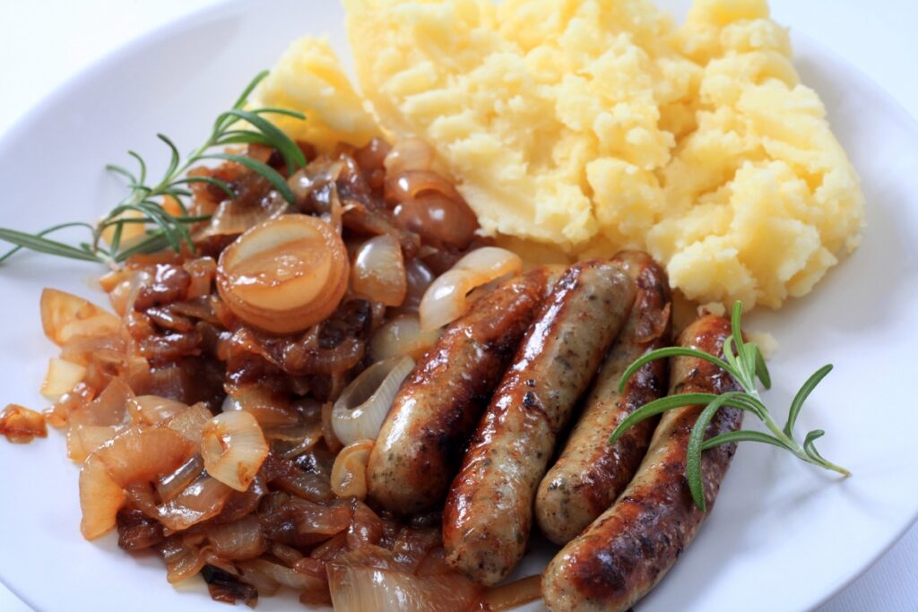 A plate of Fried Sausage With Onions And Mashed Potatoes