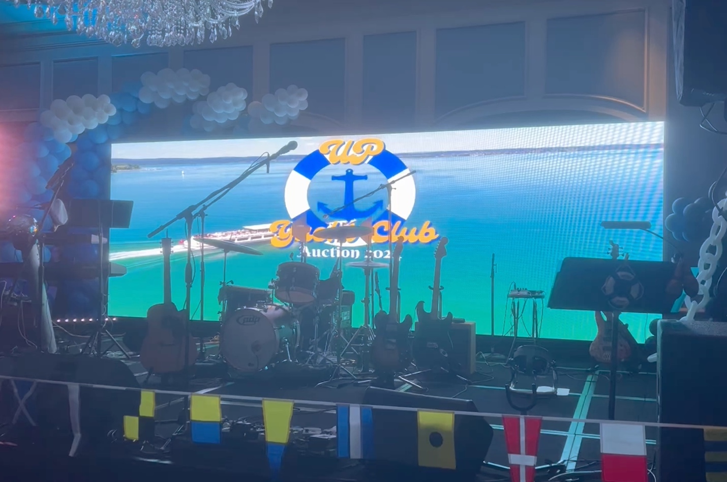 A stage with a large screen decorated
for a Sand and Sea Fundraiser.