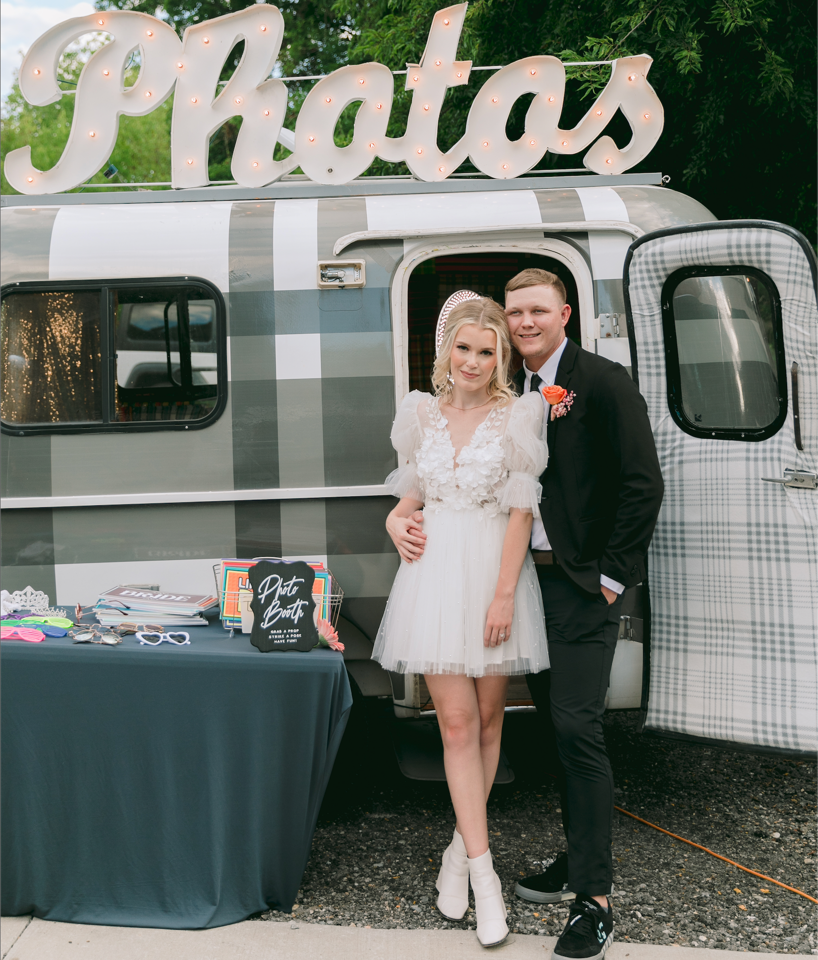 A couple standing in the door of a camper trailer for a photo trailer photo booth.