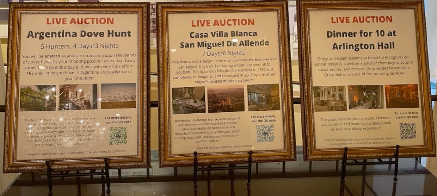 A group of live auction signs on a stand with QR codes